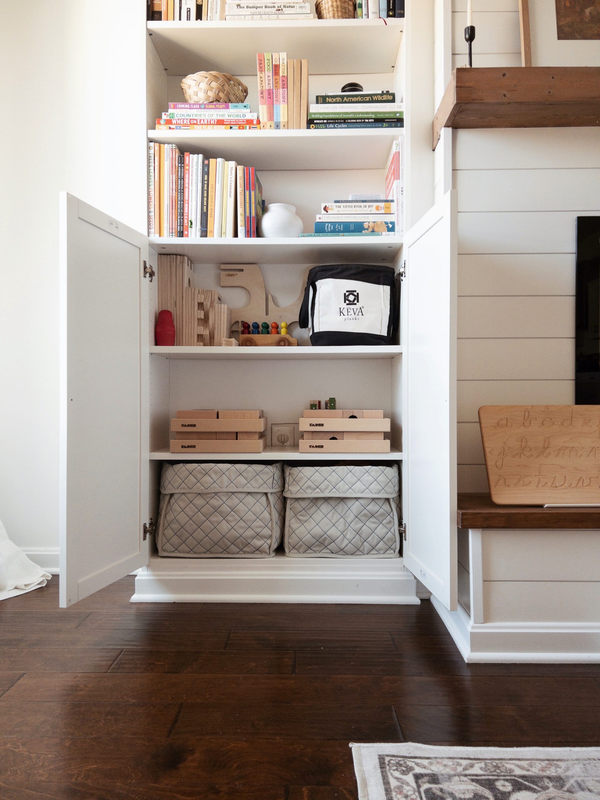 DIY Electric Fireplace with Built-In BILLY Bookcases from IKEA being used to store a variety of children's open-ended toys, including KEVA Planks and a Kaden marble run. 