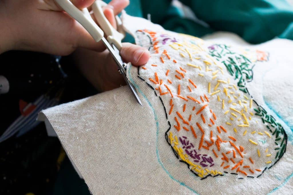 Learn how to make an embroidered biome map with your kids. You can either frame it on the wall, or you can make a cutout version by attaching a felt backing, sewing it together, and then cutting it out. It's now a fun manipulative for geography studies! Younger children may need assistance cutting the fabric once the wool felt backing has been attached. 