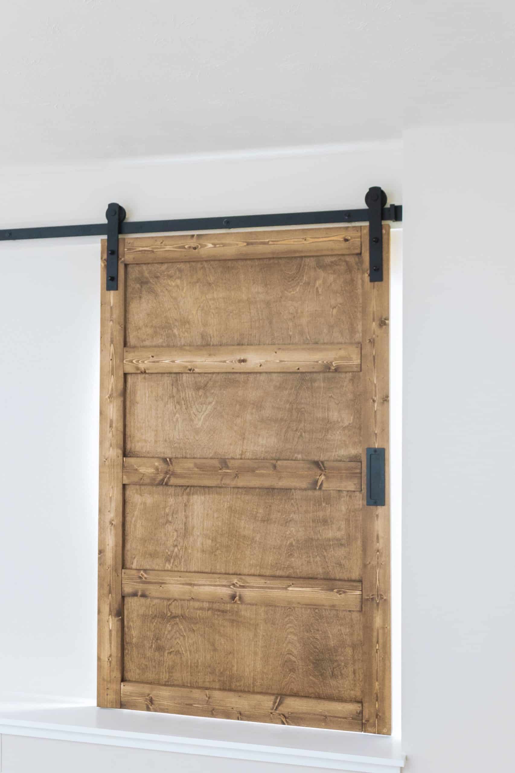 Want to build a modern farmhouse-inspired sliding barn door window covering? Head to www.freeandunfettered.com for the complete tutorial. #diyhome #modernfarmhouse #slidingbarndoor #diyhomedecor 