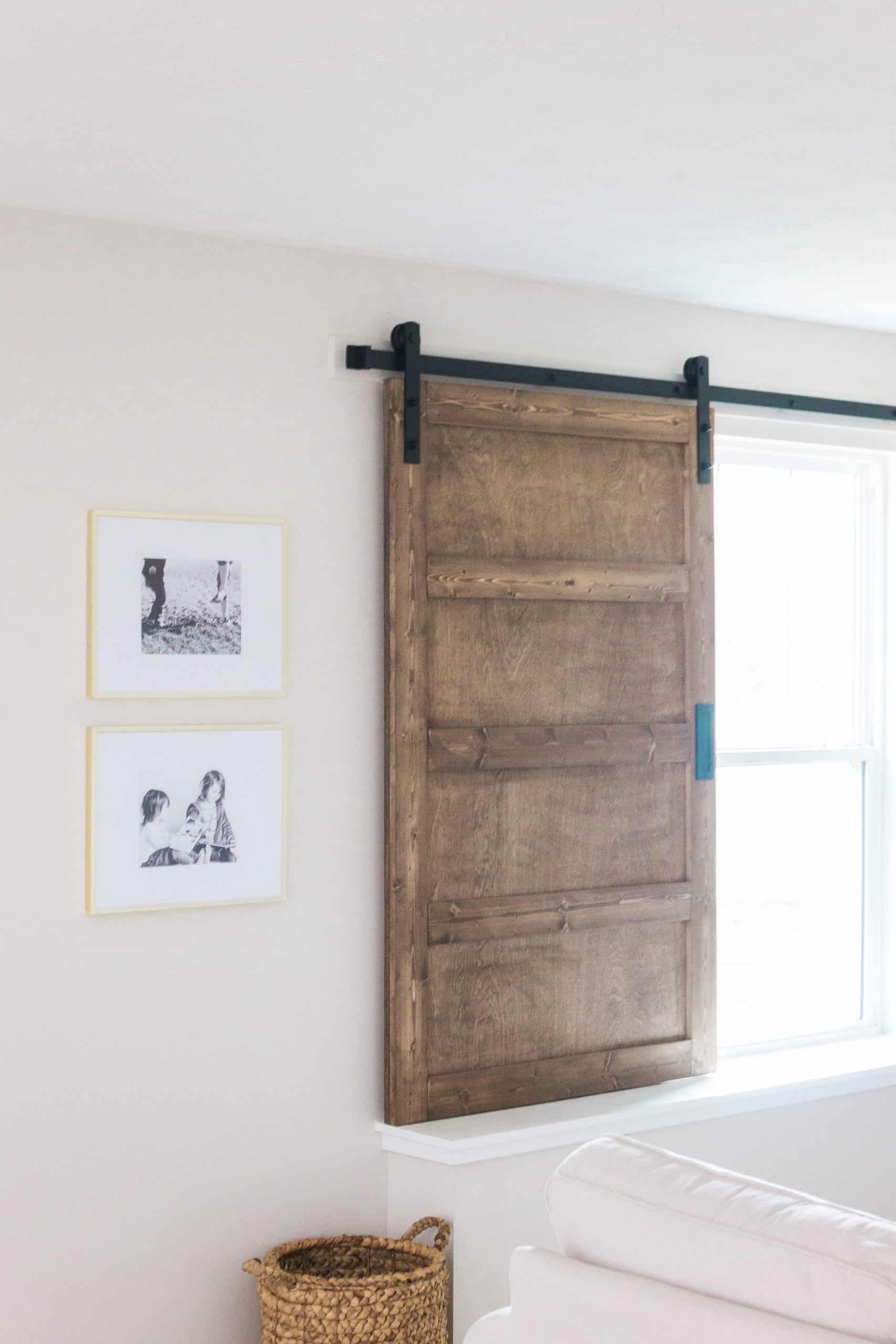 Want to build a modern farmhouse-inspired sliding barn door window covering? Head to www.freeandunfettered.com for the complete tutorial. #diyhome #modernfarmhouse #slidingbarndoor #diyhomedecor 