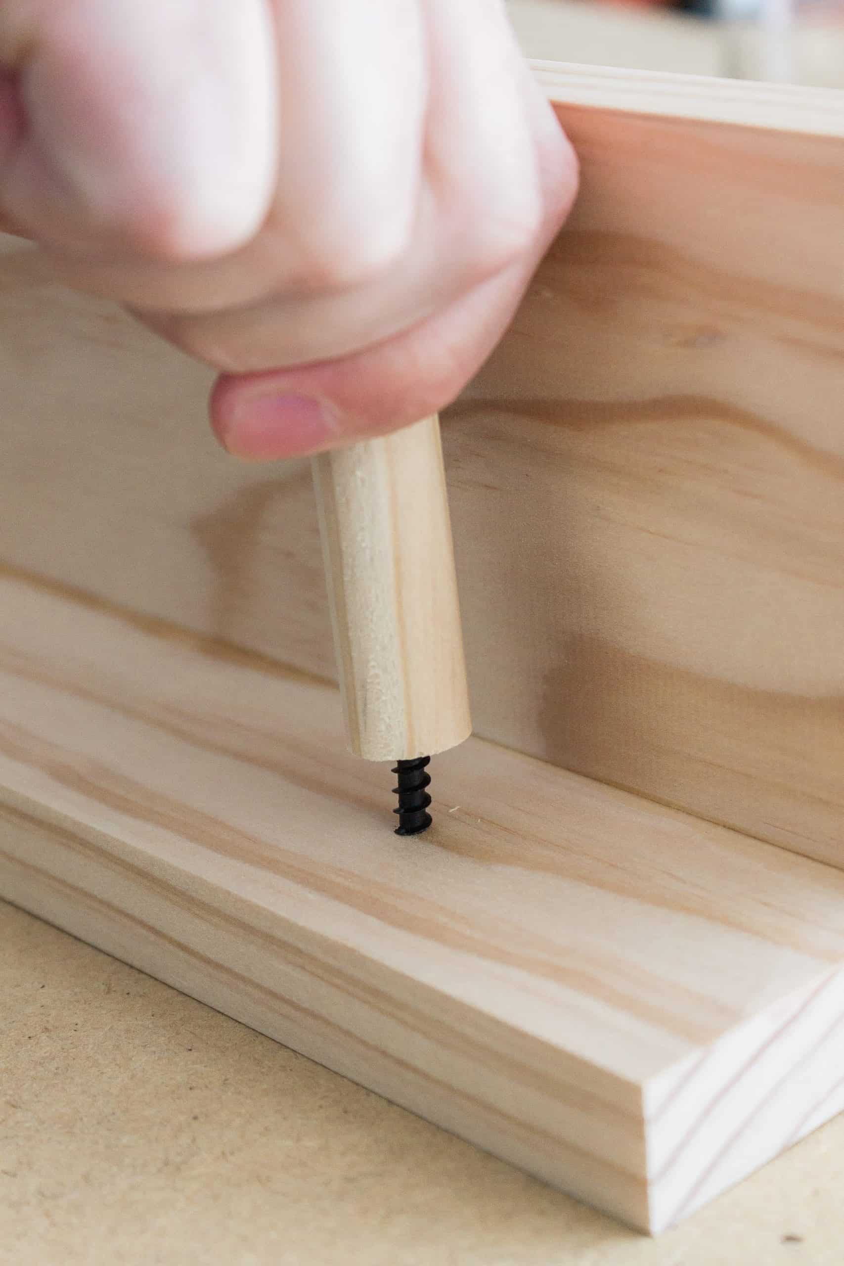 After pre-drilling the holes, simply hand screw the dowels onto the wooden peg rail shelf tight. 