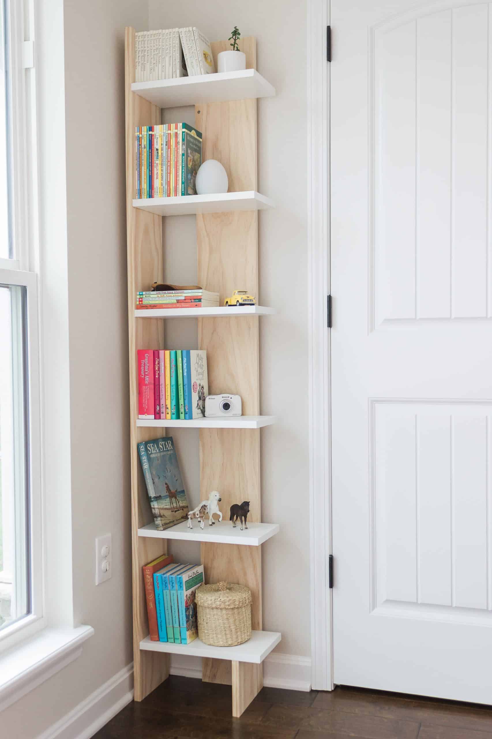 Turn into unused corner into a functional storage space with this easy-to-build and budget-friendly bookcase! You can build it in a day for just $60 dollars. See the complete tutorial at www.freeandunfettered.com. It's perfect for small space living! #diy #bookcase #bookstorage #diyfurniture #modernhome #homeorganization #storageandorganization #diyproject #budgetfriendlydecor #smallspaceliving