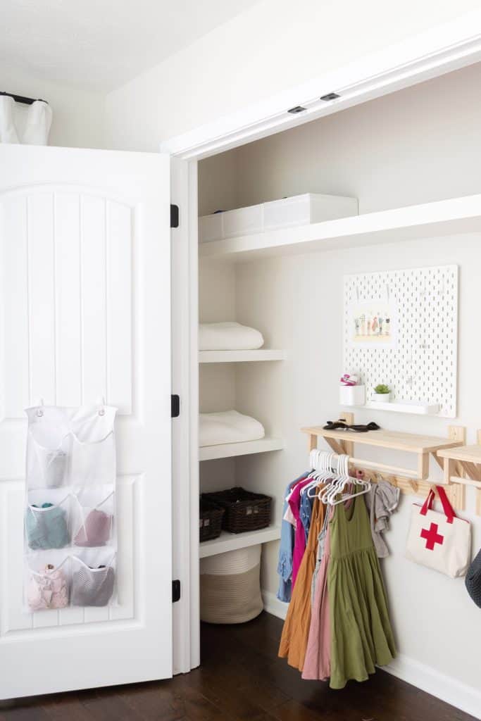 Hanging pocket organizers store children's clothing on the back of the door in a Montessori-inspired closet. Learn how to build the custom shelving shown here by visiting www.freeandunfettered.com. 